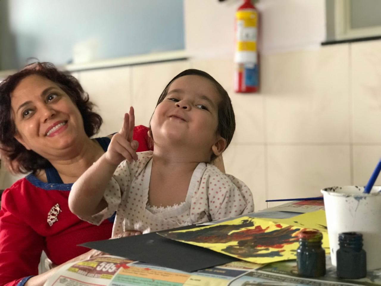 A carer and a small child painting together during the treatment program in India